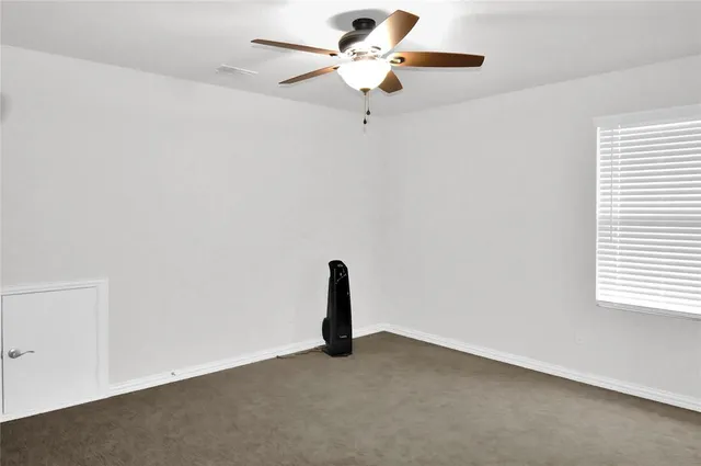 an empty room with a window and a ceiling fan