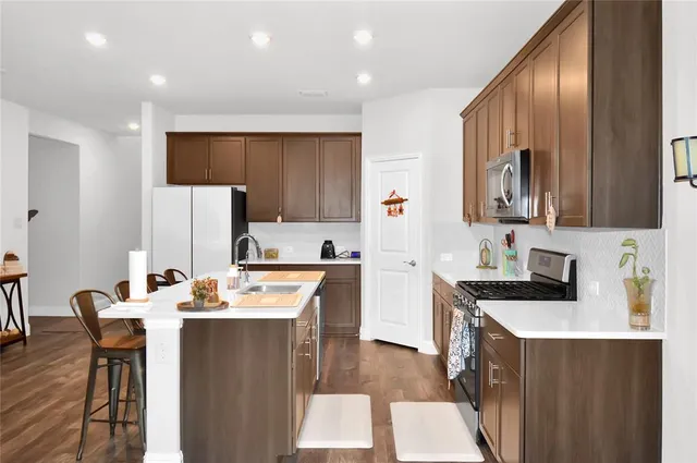 a kitchen with a sink a stove a refrigerator a dining table and chairs