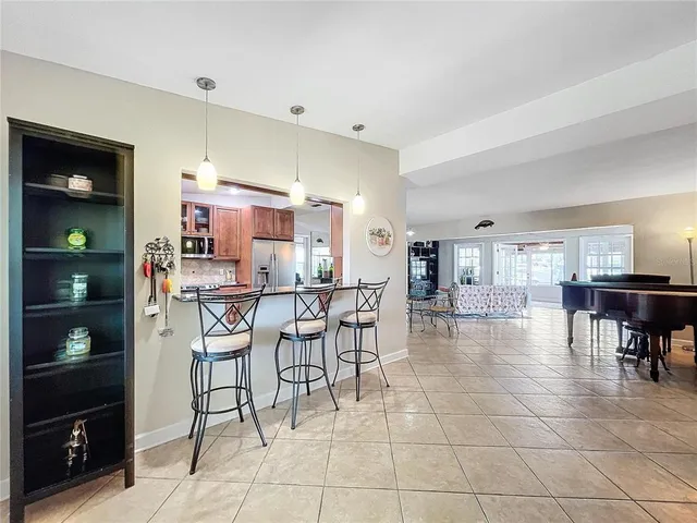 a dining room with stainless steel appliances kitchen island granite countertop a table chairs and a refrigerator