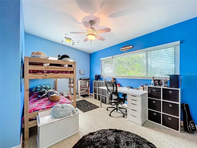 a room with furniture a flat screen tv and a ceiling fan