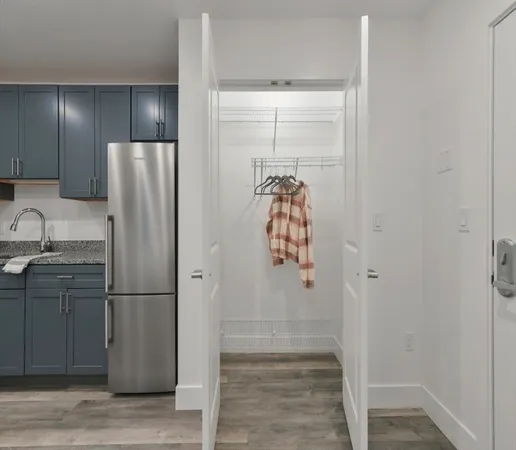 a view of a refrigerator in kitchen and an empty room