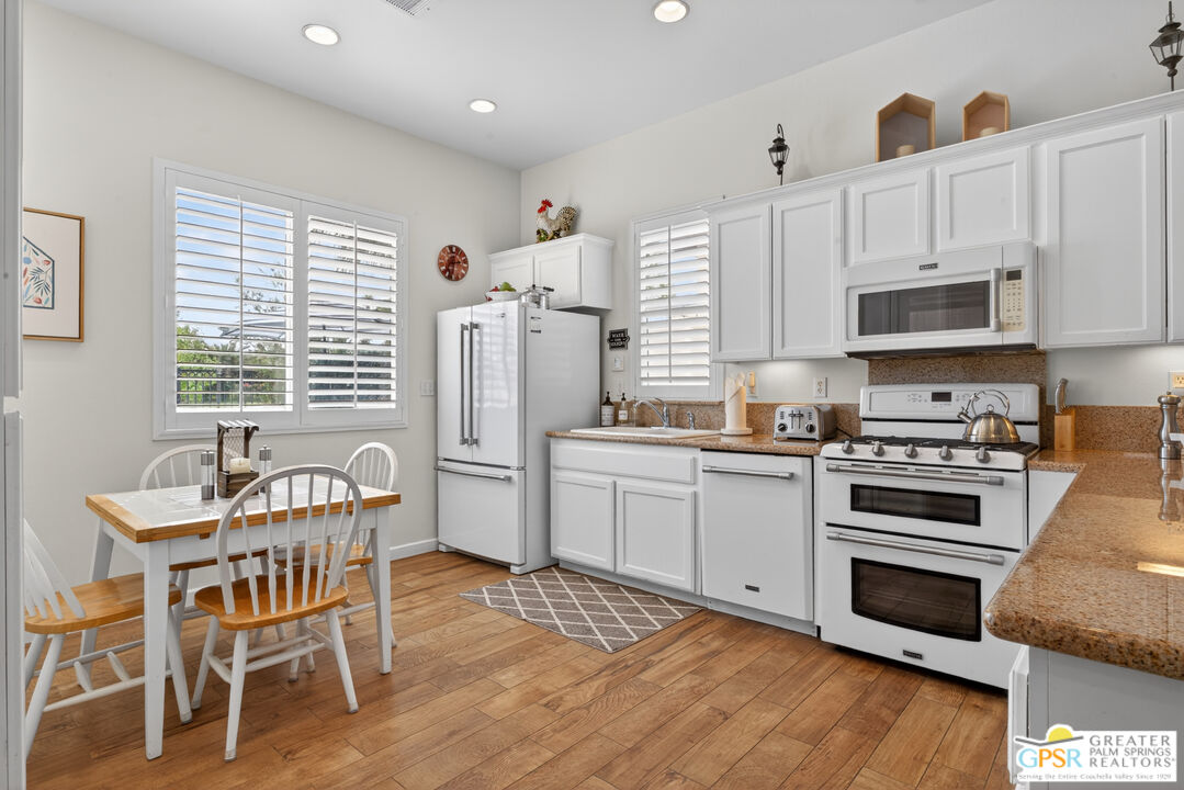 82717 Barrymore Street Indio, CA 92201 - Photo 7 of 26 a kitchen with stainless steel appliances a stove a sink dishwasher a microwave oven with a dining table and chairs