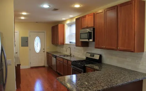 a kitchen with granite countertop a stove a sink and a wooden cabinets