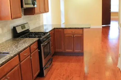 a kitchen with granite countertop a refrigerator and a stove top oven