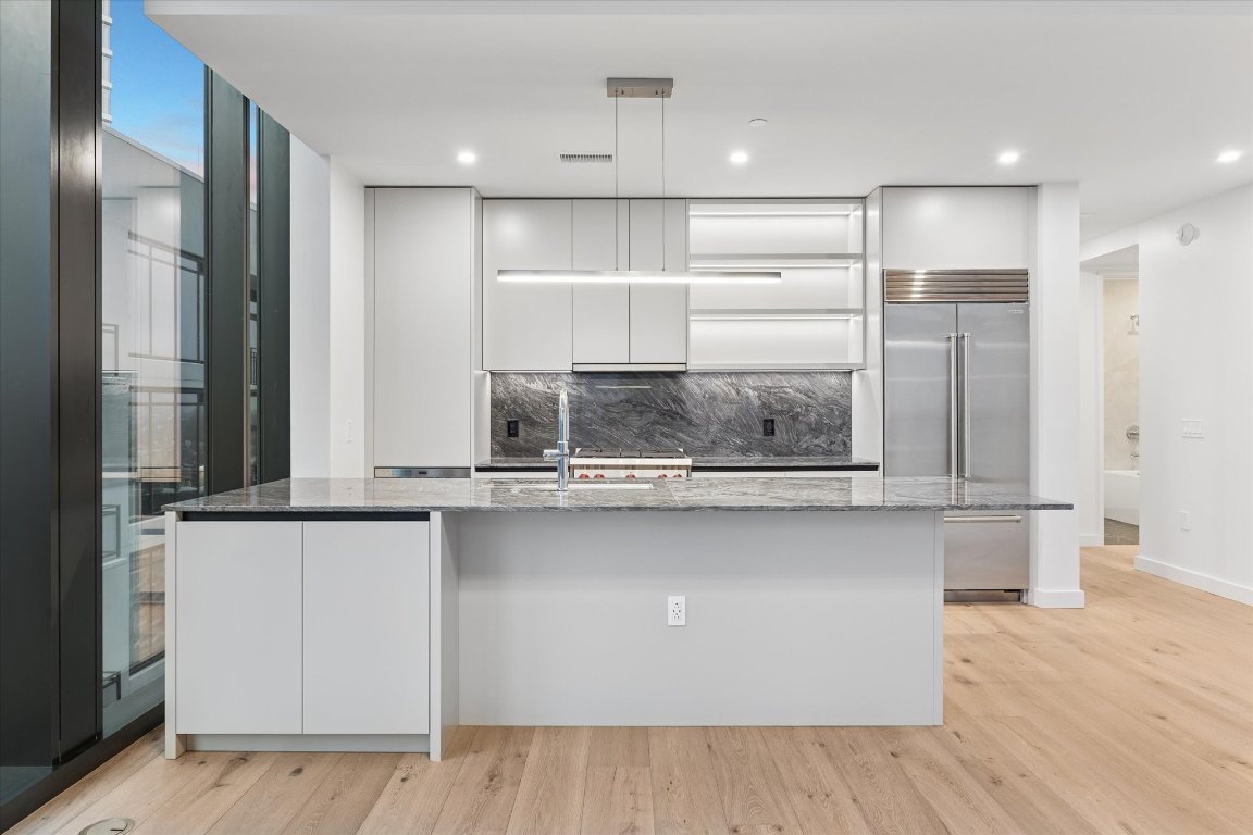 610 Davis Street, Unit 3005 Austin, TX 78701 - Photo 4 of 24 a view of a kitchen with kitchen island a sink wooden floor and glass door