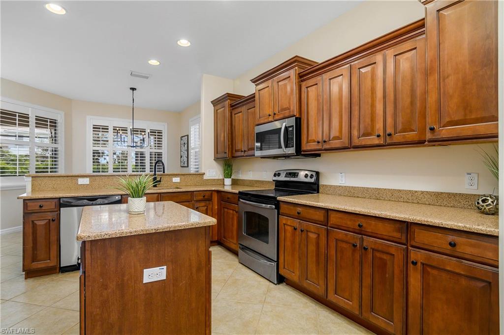 12454 Rock Ridge Lane Fort Myers, FL 33913 - Photo 7 of 37 a kitchen with stainless steel appliances granite countertop a stove a sink dishwasher and a microwave oven with wooden cabinets