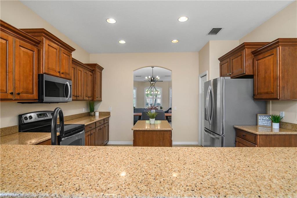 12454 Rock Ridge Lane Fort Myers, FL 33913 - Photo 8 of 37 a kitchen with stainless steel appliances kitchen island granite countertop a refrigerator and microwave