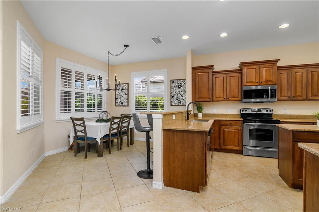12454 Rock Ridge Lane Fort Myers, FL 33913 - Photo 9 of 37 a kitchen with kitchen island granite countertop a stove top oven a sink a dining table and chairs