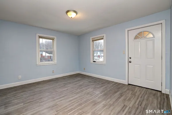 a view of an empty room with wooden floor and a window