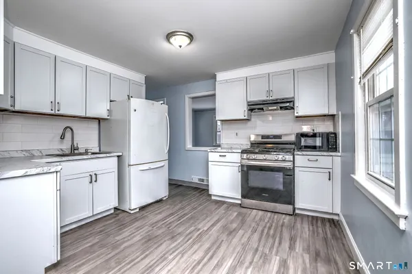 a kitchen with granite countertop white cabinets and white appliances