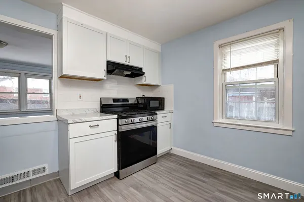a kitchen with stainless steel appliances white cabinets and a wooden floor