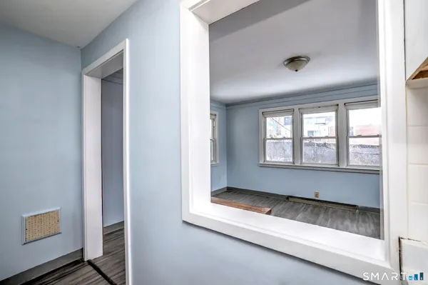 a view of an empty room with wooden floor and a window