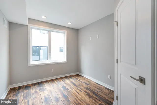 a view of an empty room with wooden floor and closet
