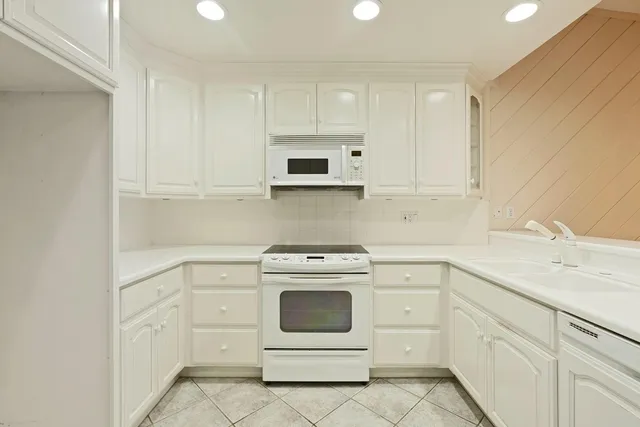 a kitchen with white cabinets appliances and sink