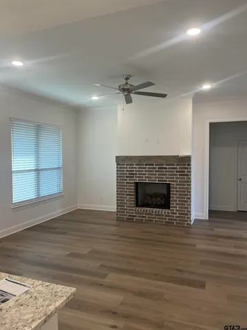 an empty room with wooden floor a fireplace and windows