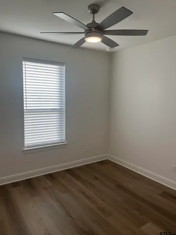 an empty room with wooden floor fan and windows