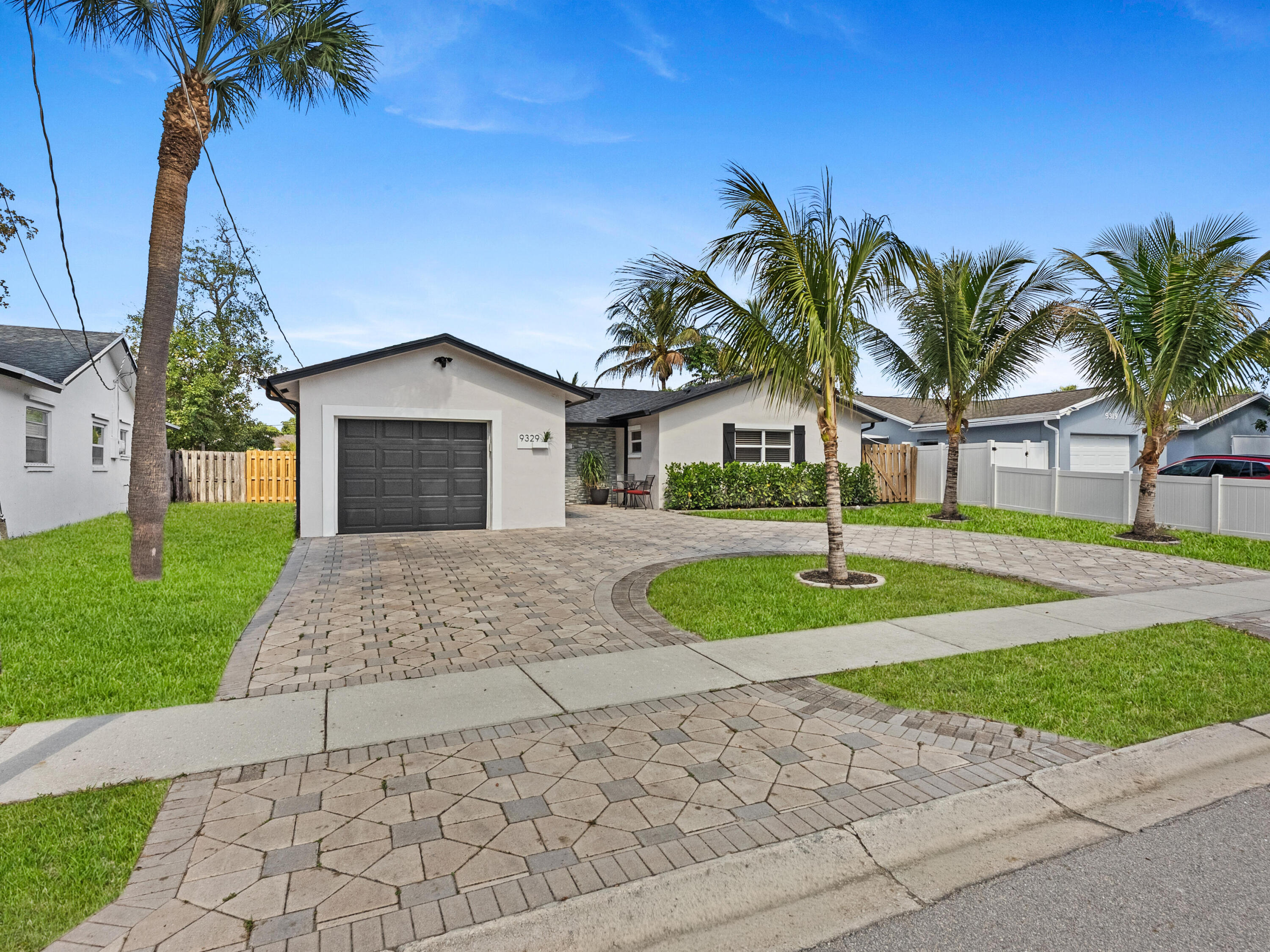 9329 Southwest 2nd Street Boca Raton, FL 33428 - Photo 2 of 42 a front view of a house with a yard and garage