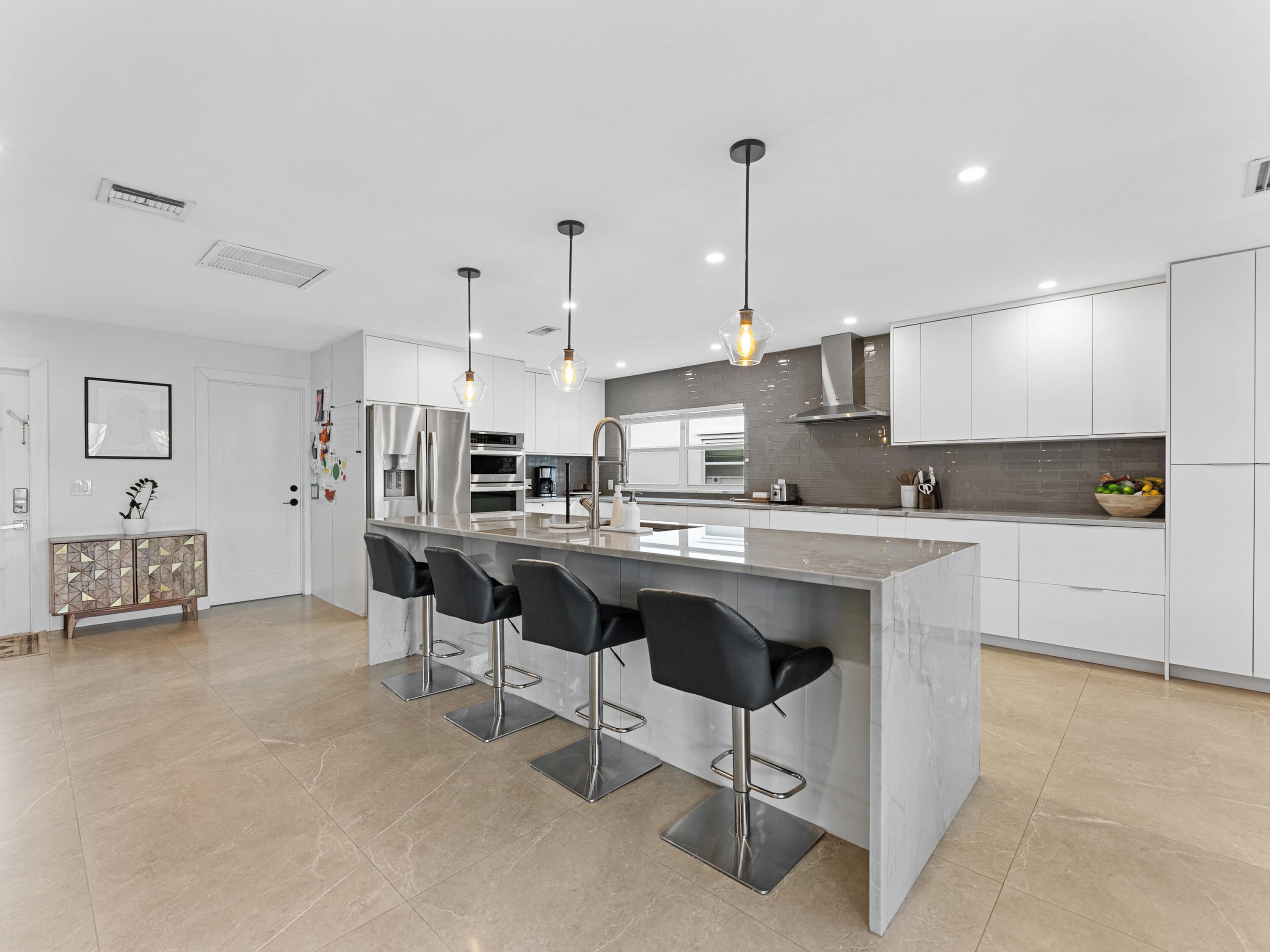 9329 Southwest 2nd Street Boca Raton, FL 33428 - Photo 6 of 42 a open kitchen with stainless steel appliances granite countertop a stove a sink a oven a dining table and chairs