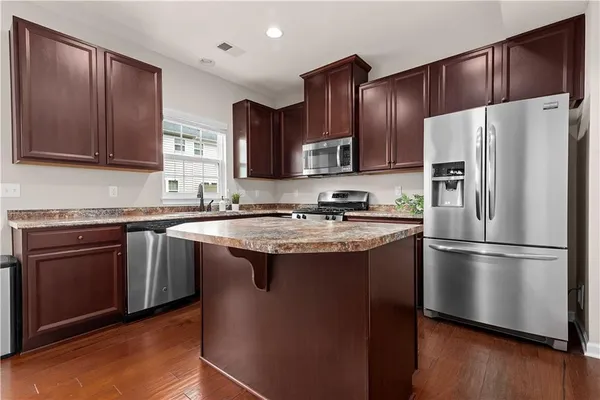 a kitchen with stainless steel appliances granite countertop a refrigerator stove a sink and a oven