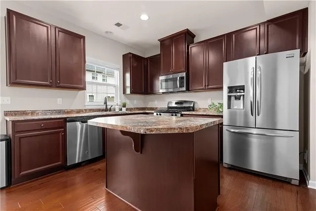 a kitchen with stainless steel appliances granite countertop a refrigerator stove a sink and a oven