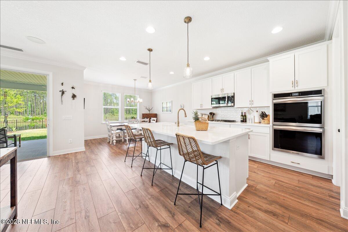 223 Tanner Trail St. Augustine, FL 32092 - Photo 4 of 44 a kitchen with stainless steel appliances granite countertop a stove top oven a sink dishwasher a dining table and chairs with wooden floor