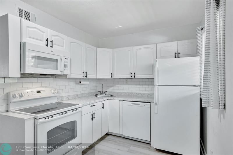 a kitchen with white cabinets sink and refrigerator