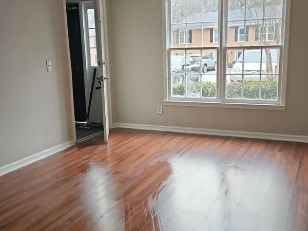 an empty room with wooden floor and windows