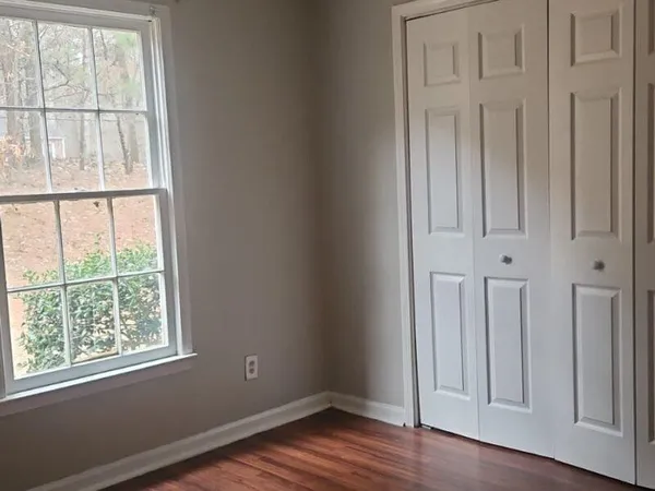 an empty room with wooden floor and windows