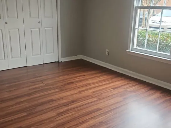 a view of an empty room with wooden floor and a window
