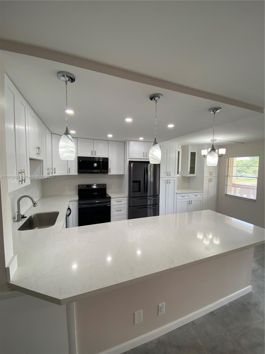 a large white kitchen with a large window and stainless steel appliances