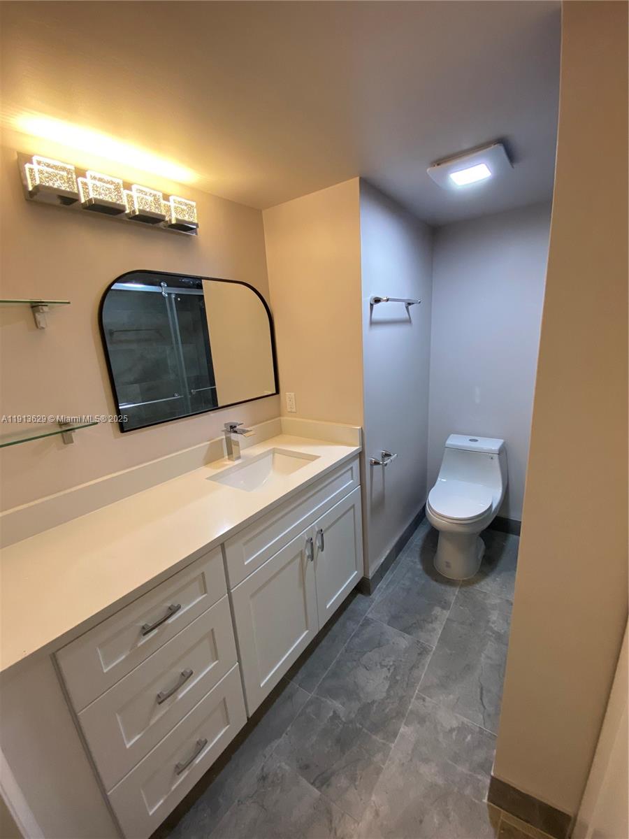 2022 Newcastle B, Unit 2022 Boca Raton, FL 33434 - Photo 8 of 21 a bathroom with a toilet sink and mirror