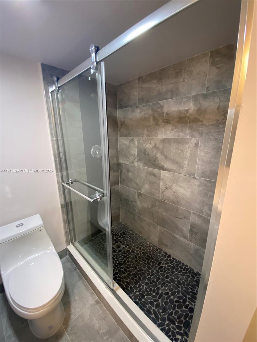 2022 Newcastle B, Unit 2022 Boca Raton, FL 33434 - Photo 9 of 21 a bathroom with a granite countertop shower and a toilet