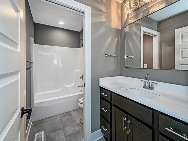 a bathroom with a granite countertop sink a toilet and shower