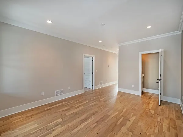 a view of an empty room with wooden floor and closet