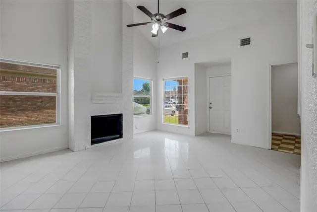 an empty room with windows and fireplace