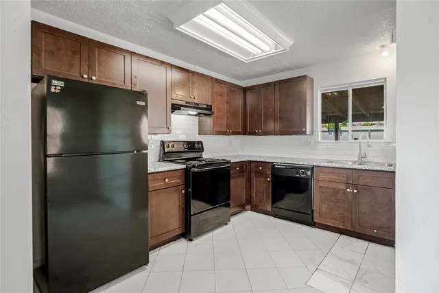 a kitchen with granite countertop a refrigerator stove top oven and sink