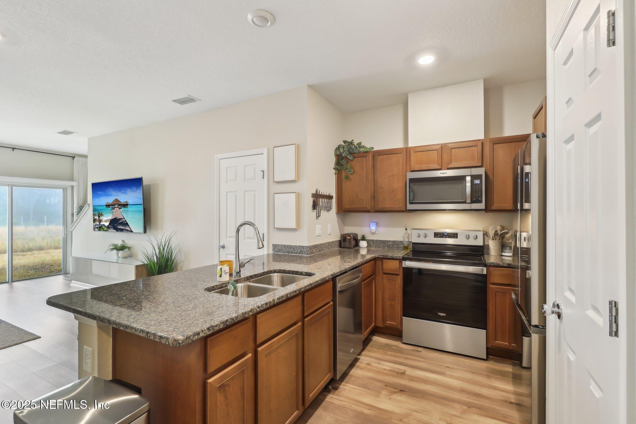 7738 Merchants Way Jacksonville, FL 32222 - Photo 12 of 29 a kitchen with stainless steel appliances granite countertop a sink stove microwave refrigerator and cabinets