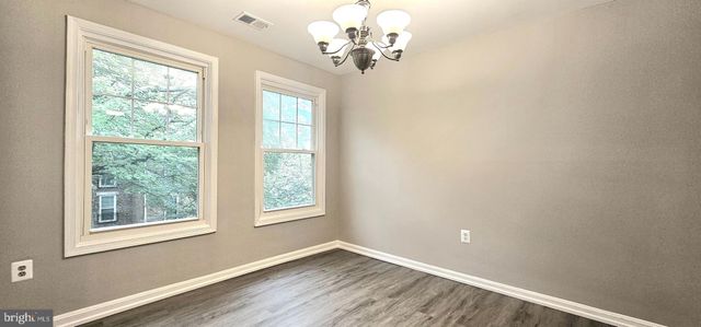 an empty room with wooden floor chandelier and windows