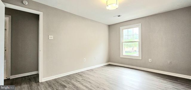 a view of an empty room with wooden floor and closet