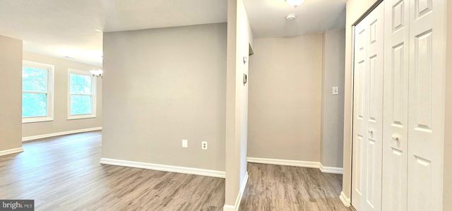 a view of a hallway with wooden floor and a bathroom