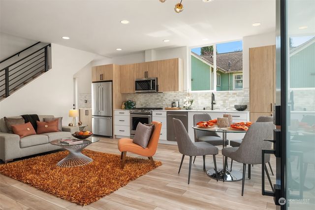 a living room with stainless steel appliances kitchen island granite countertop a couch and white cabinets