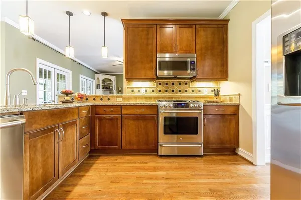 a kitchen with stainless steel appliances granite countertop a stove a sink and a microwave