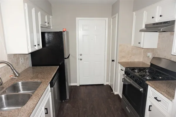a kitchen with granite countertop a sink stove and refrigerator