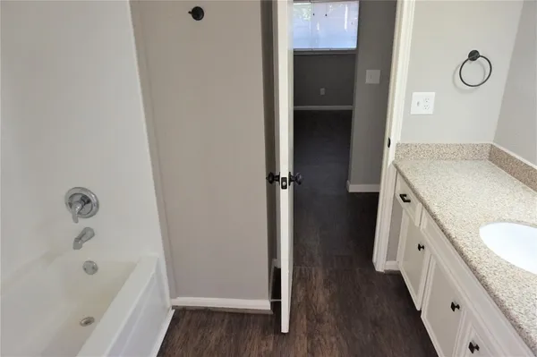 a bathroom with a granite countertop sink a mirror and a bathtub