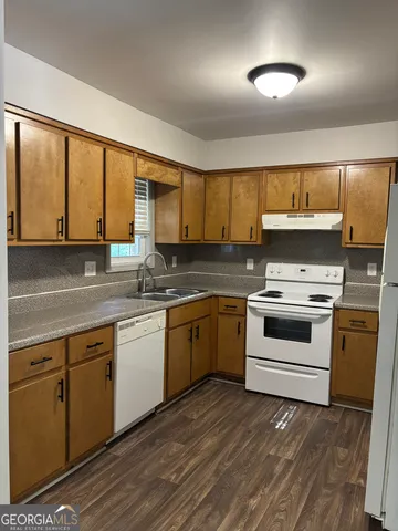 a kitchen with granite countertop a stove a sink and a granite counter tops with wooden floors