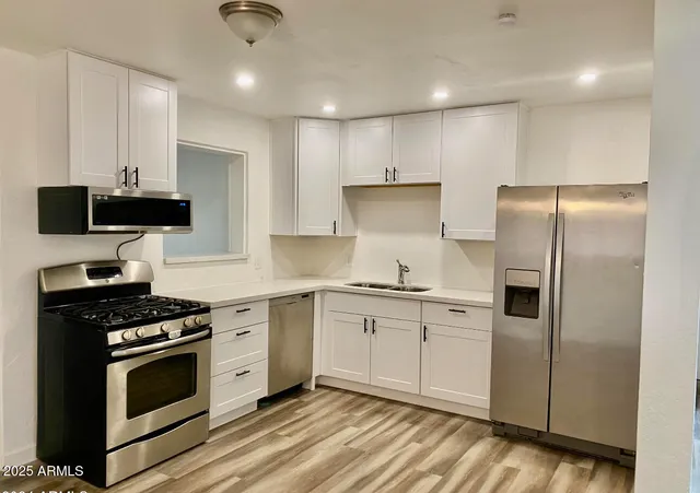 a kitchen with stainless steel appliances a stove a sink and a refrigerator