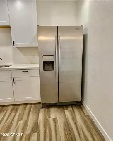 a view of a refrigerator in kitchen and an empty room