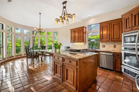 a kitchen with kitchen island granite countertop a stove a sink a refrigerator and a dining table with wooden floor