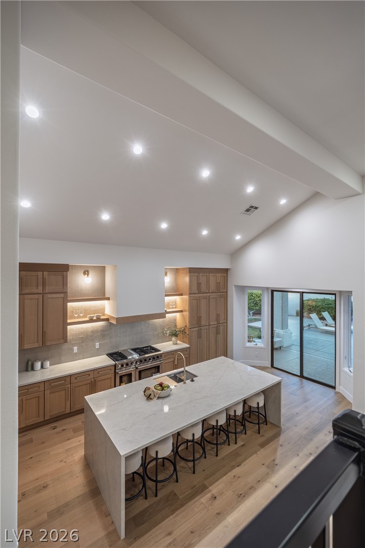 8800 Lusso Las Vegas, NV 89134 - Photo 59 of 85 Kitchen featuring a breakfast bar area, light wood-type flooring, light stone counters, recessed lighting, and double oven range