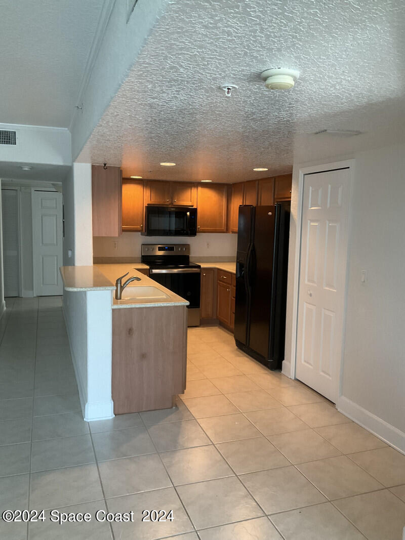 2035 Florida A1A, Unit 201 Satellite Beach, FL 32937 - Photo 8 of 12 a kitchen with stainless steel appliances granite countertop a stove a refrigerator and a sink